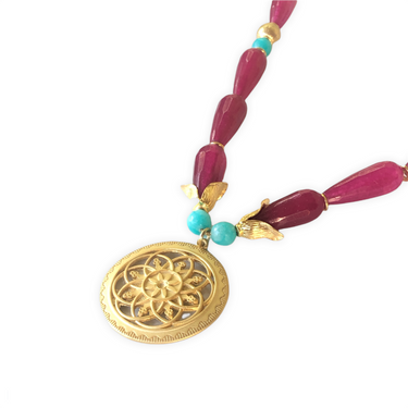 Collar corto con una espectaculares lágrimas de ágatas facetadas burdeos, howlite turquesa y zamak con baño de oro mate. Este collar tiene una preciosa pieza central de un medallón con flor que seguro conseguirán resaltar tu look favorito. Detalle